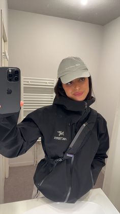 a woman taking a selfie in the bathroom with her cell phone and hat on