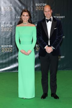 two people in formal wear standing next to each other on a green carpeted floor