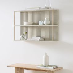 a shelf with vases and books on it next to a wall mounted bookcase