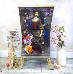 a dresser with flowers and a painting on it