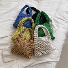 four purses sitting on top of a bed next to each other in different colors