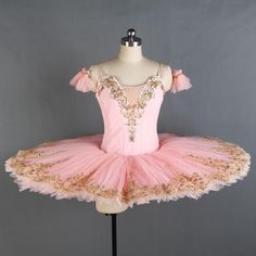 a pink tutu dress with gold sequins on the top and bottom, sitting on a mannequin