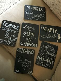 four black and white signs that are on a couch in front of a pillow with writing on them