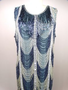 "This is an EXQUISITE and RARE vintage dress! It's heavily embellished and beautifully detailed with glass beading in an Art Deco \"waterfall\" design. It's in excellent condition! Please note, this piece has a 7\" inch long side zipper and several hook and eye closures. It's very well made and weighs approximately 6 lbs. Bust - 44/46\" Waist - 42/44\" Hips - 46/48\" Length - 39\" This dress comes from a pet-free and smoke-free home. If you would like more info or have any questions, please don' Gatsby Style Sleeveless Embellished Evening Dress, Gatsby Style Embellished Sequin Cocktail Dress, Gatsby Style Sleeveless Embellished Flapper Dress, Sleeveless Gatsby Embellished Flapper Dress, Embellished Sleeveless Flapper Dress For Wedding, Sleeveless Embellished Flapper Dress For Wedding, Wedding Embellished Sleeveless Flapper Dress, Wedding Sleeveless Embellished Flapper Dress, Vintage Sleeveless Dress With Beaded Fringe