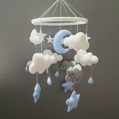 a baby crib mobile with clouds, stars and a teddy bear hanging from it