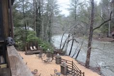 an outdoor dining area next to a river with chairs and tables on the sand by the water