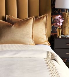 a close up of a bed with two pillows and a lamp on the side table