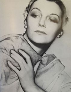 a black and white photo of a woman with her hands on her chest, looking off to the side