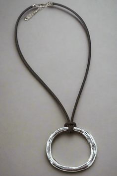 This Rippled Oval Pendant Short Thick Leather Cord Necklace is a stylish accessory that combines a trendy design with durability. Made with a thick leather cord and a unique rippled oval pendant, this necklace is perfect for everyday wear or special occasions. Upgrade your outfit with this versatile and eye-catching necklace. Details:- Genuine Leather Cord- Adjustable by 2"- Simple Hammered Oval Pendant Dimensions:- Approx. 16" Length- Extendable by 2"- Pendant Size: 1.5" x 2" Short And Thick, Leather Cord Necklace, Leather Corded Necklace, Loose Fitting Tops, Oval Pendant, Cord Necklace, Stylish Accessories, Vintage Accessories, Leather Cord