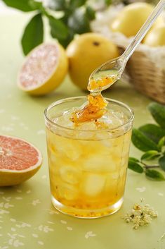 a glass filled with liquid next to grapefruits