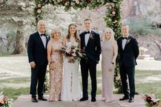 a group of people standing next to each other in front of a flower covered arch