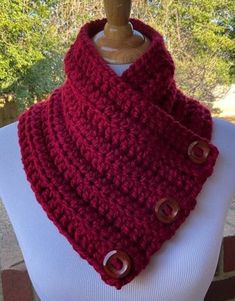 a close up of a mannequin wearing a red scarf with buttons on it