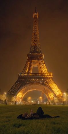 the eiffel tower lit up at night with people laying in front of it