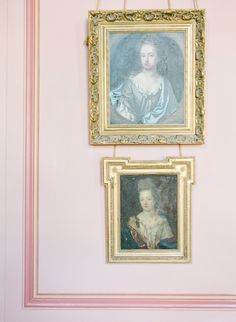 two paintings hang on the wall in a room with pink walls and gold trimmings