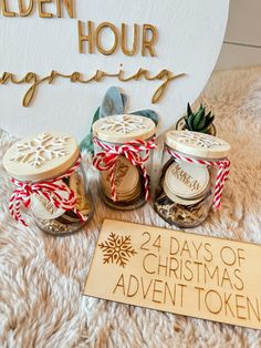 three jars filled with christmas cookies next to a wooden sign