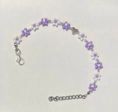 Nothing says warm weather and sun-soaked days like lightweight daisy chains and lavender! This beautiful bracelet is hand-crafted using glass seed beads and a silver zinc alloy heart charm in the middle. These gorgeous little flower chains are also adjustable in length with the extra 1 inch chain and lobster claw closure, while being strung on invisible string that stretches! This bracelet is dainty, elegant, and cute while also being so weightless it feels like you aren't even wearing a bracelet! Flower Beads Bracelet, Lavender Bracelet, Glass Bead Jewelry, Daisy Chains, Invisible String, Clay Bead Necklace, Diy Jewelry Unique, Fancy Jewellery Designs, Daisy Bracelet