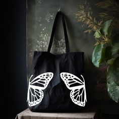 "This Butterfly Tote Bag will be your next everyday bag. Whether it's used as a grocery bag, school bag, or as a work bag; it will be the perfect bag or yourself to give as a gift.  The minimalist design will match everything but is unique enough can stand out on its own! Standard Tote Bag Classic Canvas 100% Cotton Dimensions: 15\"W x 16\"H , 21\" Handles Large Canvas Tote Bag Heavy Canvas with squared off bottom Dimensions: 20\"W x 15\"H x 5\"D , 23\" Handles Heavy Canvas Zipper Tote Bag  Heav Reusable Tote Canvas Bag For Daily Use, Reusable Black Bag For Everyday Use, Recyclable Everyday Bags For Back To School, Reusable Shoulder Bag For School, Casual Recyclable School Bag, Large Everyday Reusable Bags, Reusable Canvas Bag For Everyday Use, Reusable School Tote Bag, Large Everyday Reusable Bag