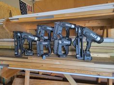 four black and decker drillers sitting on top of a wooden shelf