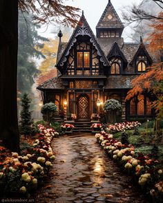 a house in the woods with lots of flowers and trees around it on a rainy day