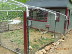 a chicken coop in the middle of a yard with rocks and grass on the ground