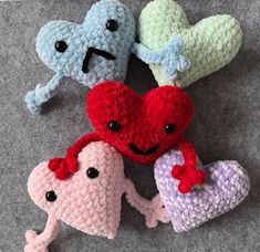 four crocheted hearts are sitting on the floor