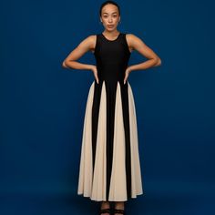 a woman standing in front of a blue background wearing a black and white dress with two toned panels