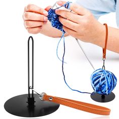 a person is knitting yarn on a hook with a pair of scissors and a ball of yarn