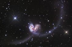 two spiral shaped objects in the middle of a black sky filled with stars and dust