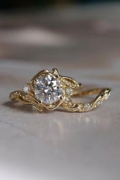 two gold rings with diamonds on them sitting on top of a white countertop next to each other