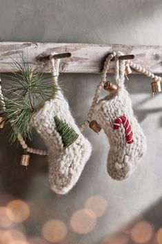 two knitted stockings hanging from a wooden rack with bells and pine cones on them