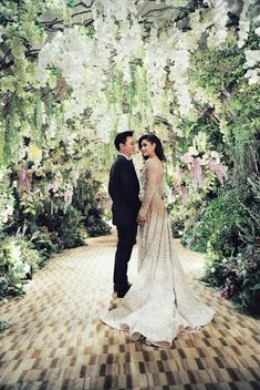 a newly married couple standing in front of a floral archway