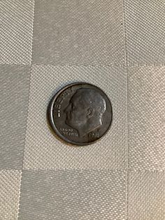 a penny sitting on top of a checkered table cloth with the image of a man's head