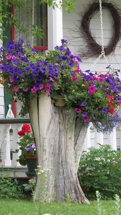 a tree stump with flowers in it and a wreath hanging on the side of it