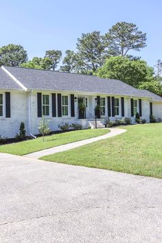 a white house with black shutters and green grass