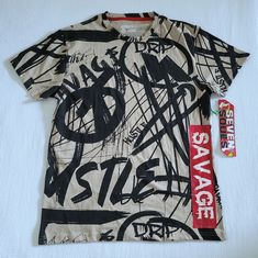 Brand New With Tags Seven7 Souls Graffiti Tee Excellent Condition With No Flaws Size Medium Approx Measurements Laying Flat Length 27.5" Armpit To Armpit 20" Across Bottom Hem 20.5" 60% Cotton 40% Polyester Color Of Tee Is Khaki With Black Graffiti On Front And Back With Words "Drip", "Hustle", "Savage" Red Vertical "Savage" Banner On Left Front In White Letters Crew Neckline, Short Sleeves, Straight Hem Please No Trades Or Lowballs! *Ask Any Questions You May Have Prior To Making An Offer Or Pu Casual Beige Shirt With Graphic Print, Casual Beige Graphic Print Shirt, Black Graffiti, Brothers Shirts, Stitch Shirt, Red Tee, Rap Tee, Rock T Shirts, Vintage Carhartt