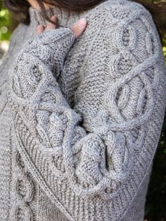 a close up of a person wearing a sweater with an intricate design on the sleeves