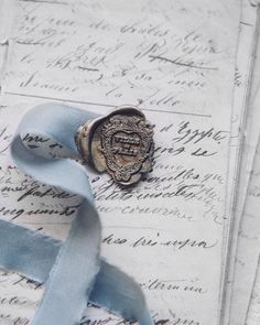 a waxed seal sitting on top of an old letter with blue ribbon around it