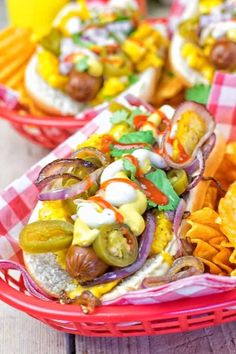 two baskets filled with hot dogs covered in toppings next to chips and ketchup