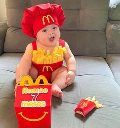 a baby in a mcdonalds costume sitting on a couch next to a box of fries