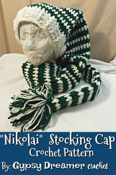 a crochet hat and scarf sitting on top of a white table with the words nikla stocking cap written below it