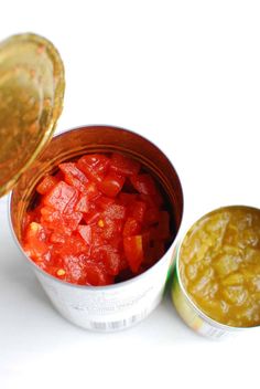 two tins filled with food sitting on top of a white table next to each other