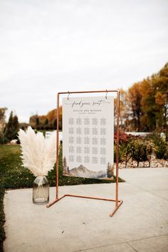 a sign that is on top of a stand with some flowers in the vase next to it