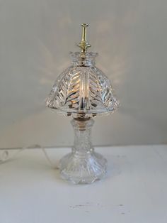 a clear glass table lamp with a metal base and a light bulb on the top