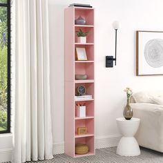 a pink bookcase in a white room with a window and potted plant next to it