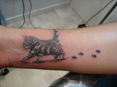 a person with a cat tattoo on their arm and paw prints all over the wrist