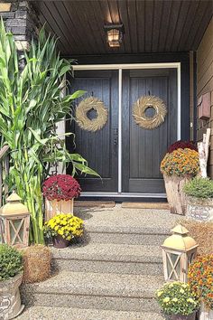 the front door is decorated with wreaths and potted plants for fall decorating