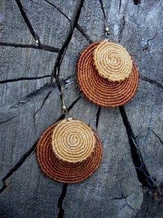 two brown and white earrings sitting on top of a rock