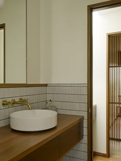 a bathroom sink sitting on top of a wooden counter next to a mirror and door