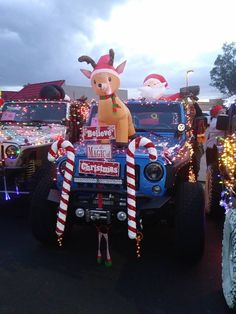 a jeep decorated with christmas lights and decorations in the shape of a reindeer on top