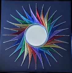 a colorful starburst made out of colored pencils on a blue surface with a white circle in the middle